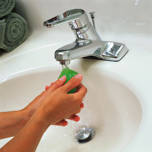Hands holding a bar of soap under running water in a sink